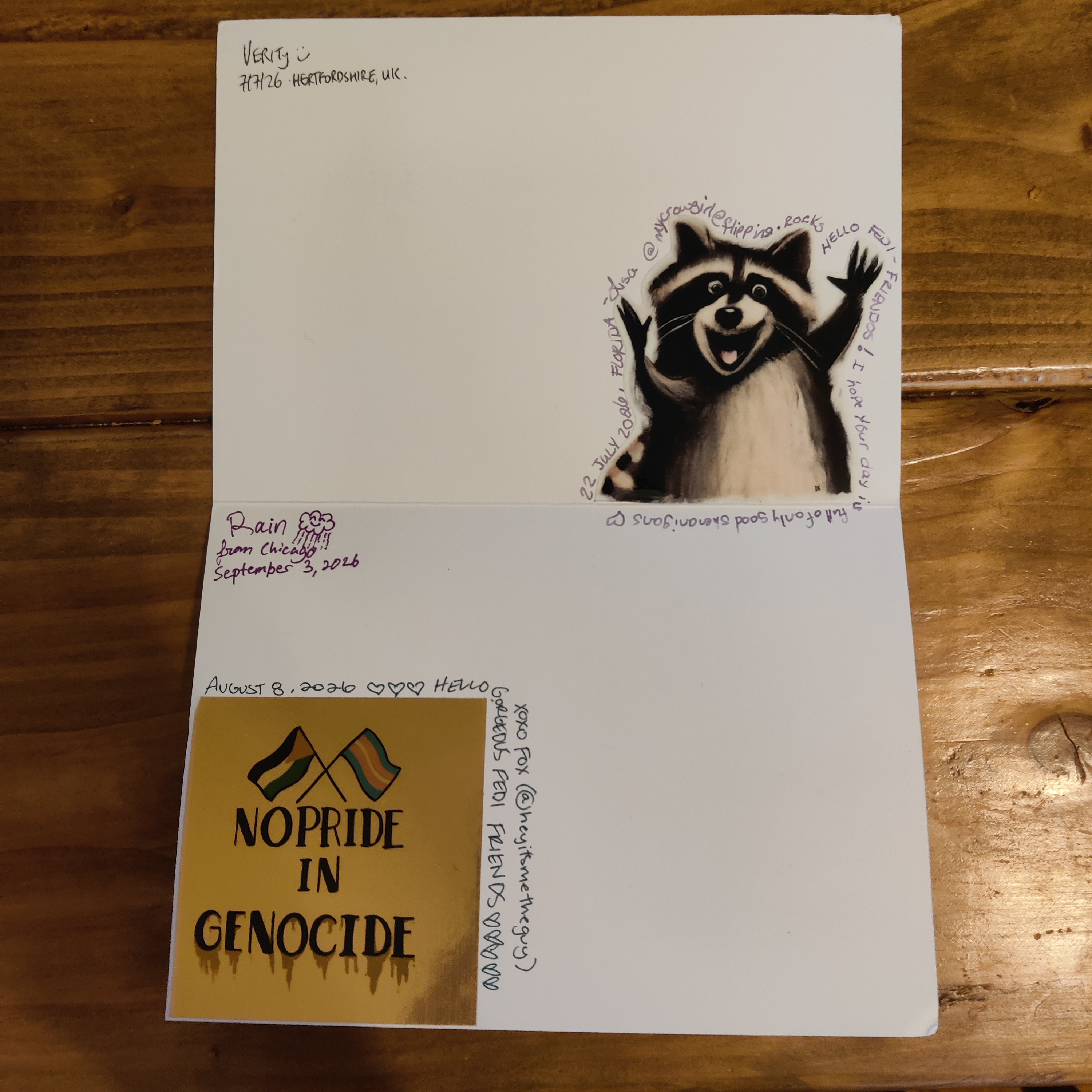 the inside of a greeting card with several signatures. One signature wraps around a 'no pride in genocide' sticker showing crossed Palestine and trans flags. One wraps around a sticker of a raccoon throwing its hands up and looking goofy.
